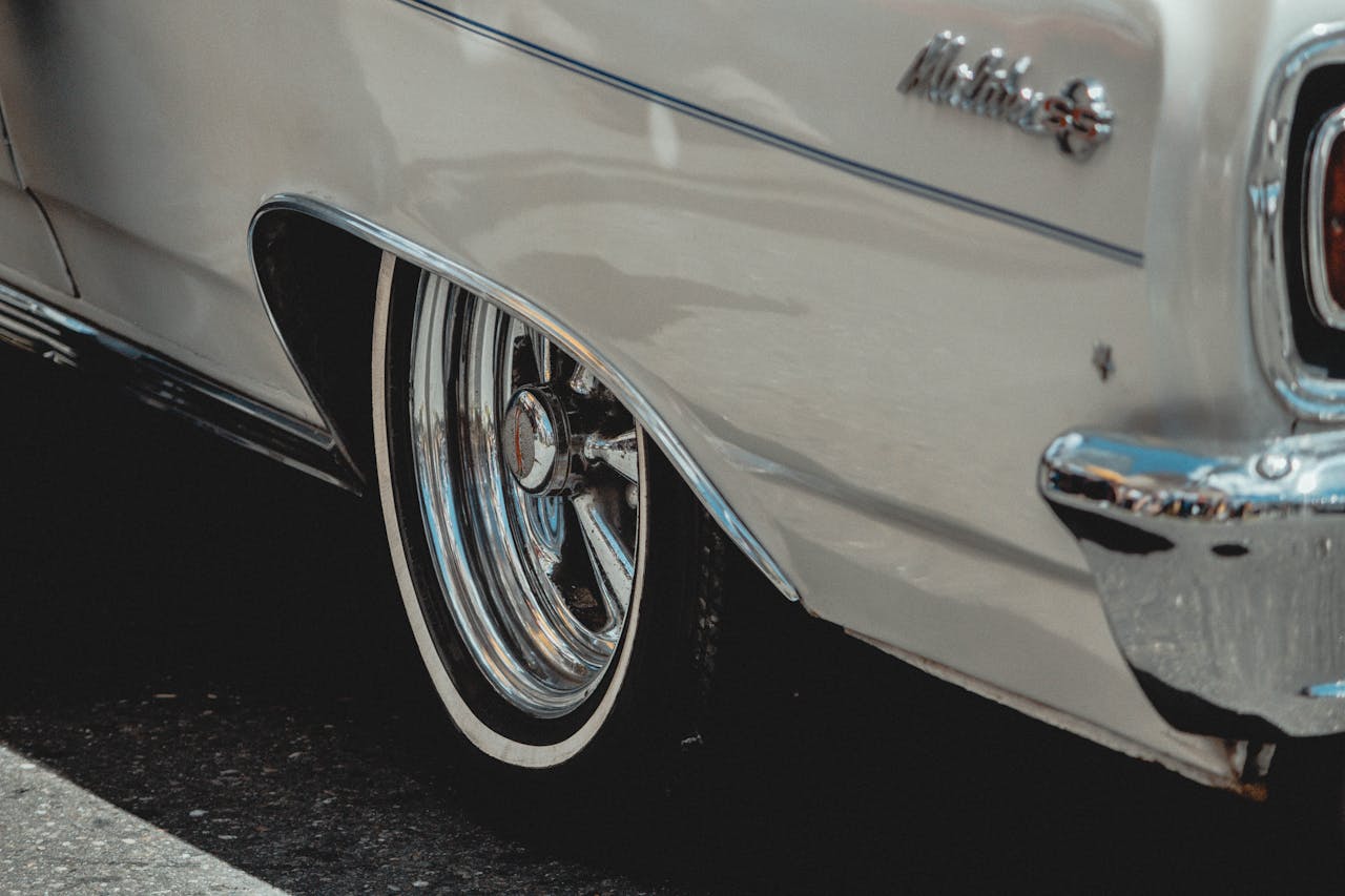 Close-up of a vintage car's chrome bumper and wheel, showcasing classic retro design and metallic shine.