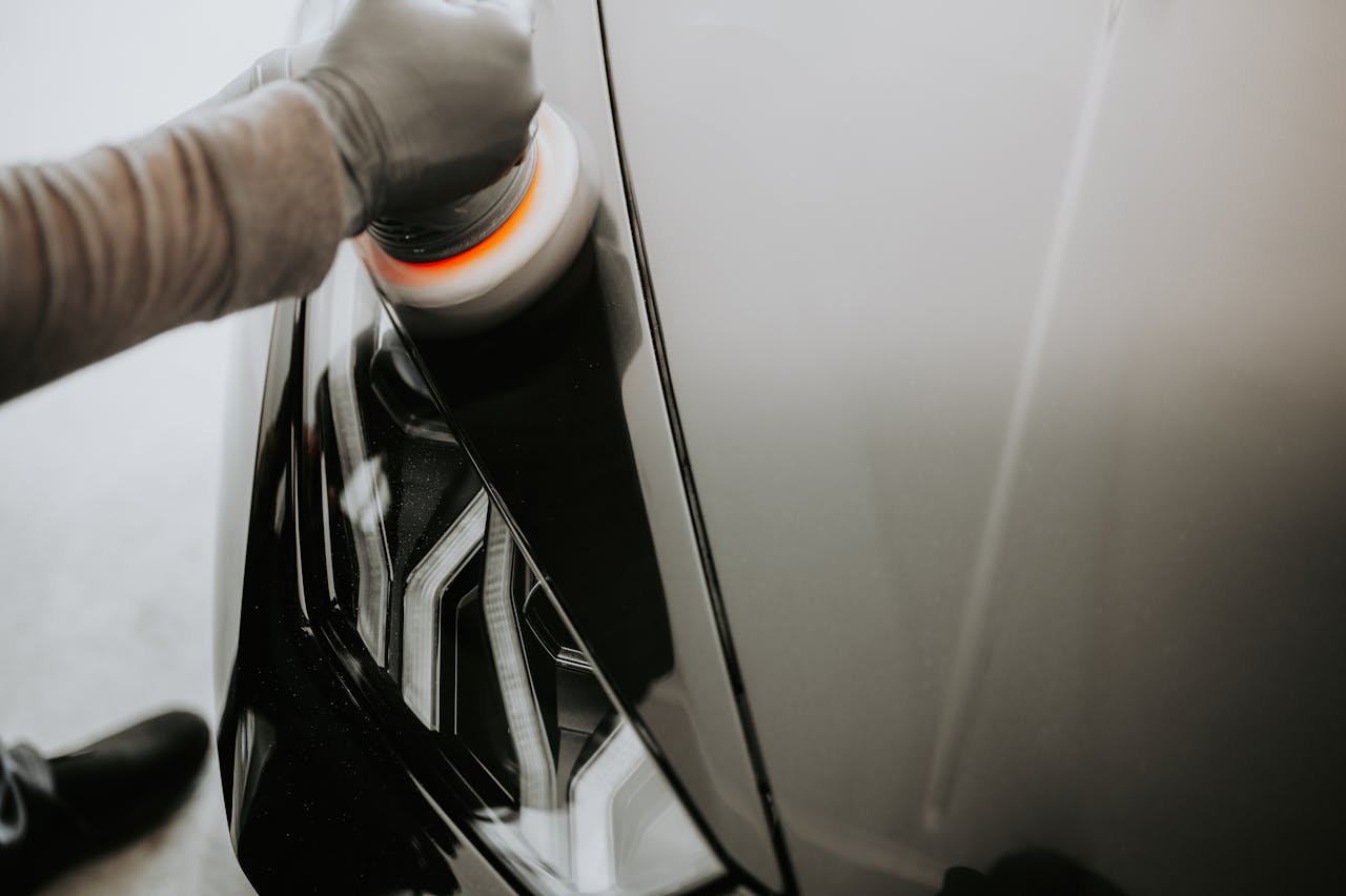 about-01 Close-up view of a person polishing a black car using a buffing machine.