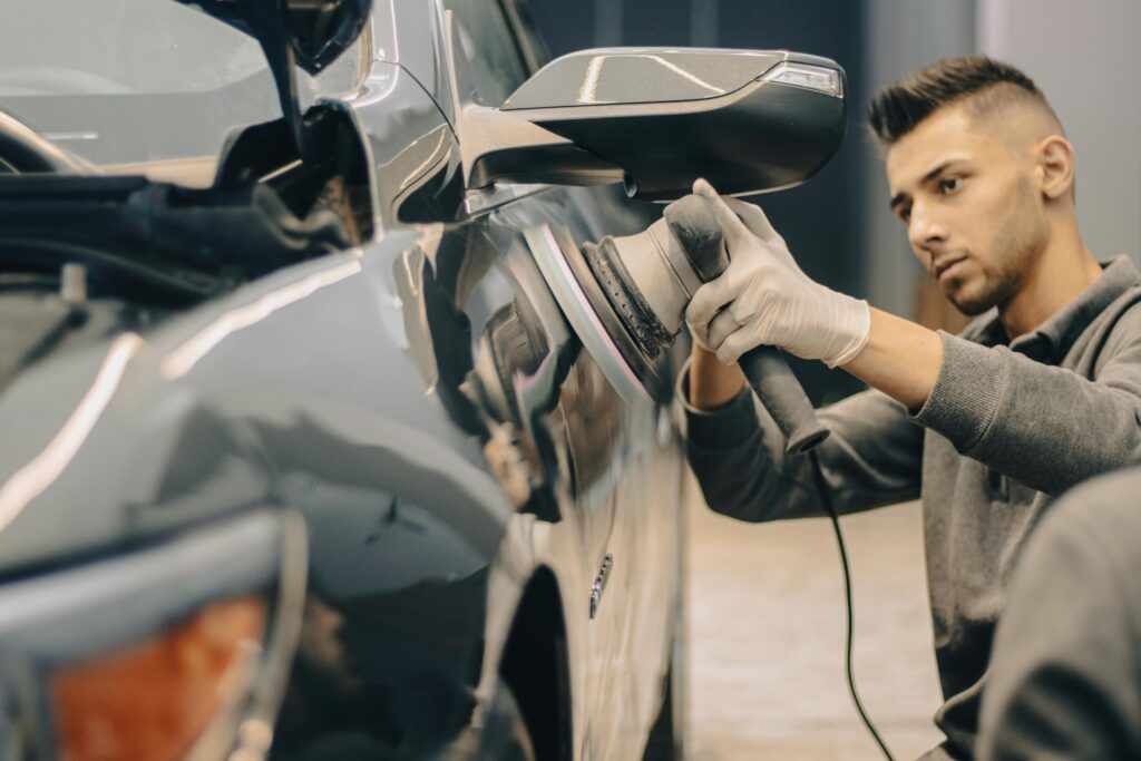 pexels-photo-14615269-14615269 A focused worker polishes a vehicle with precision, enhancing its shine indoors.