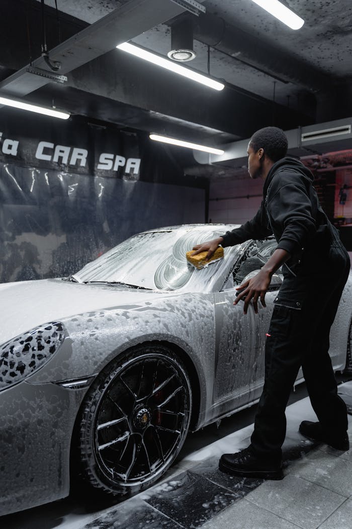 gallery-6 Employee in uniform cleaning a luxury car with foam at an indoor car spa.